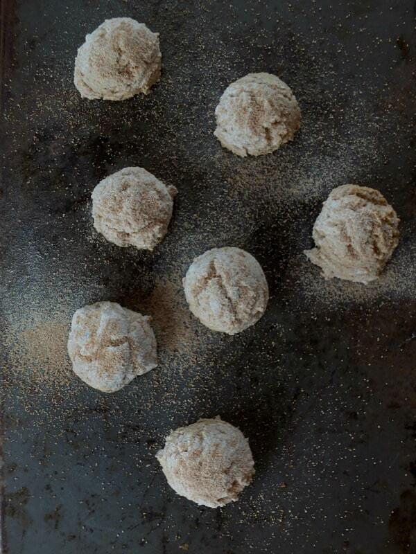 gluten free snowball cookies on a baking sheet with cinnamon sugar spinkled on top