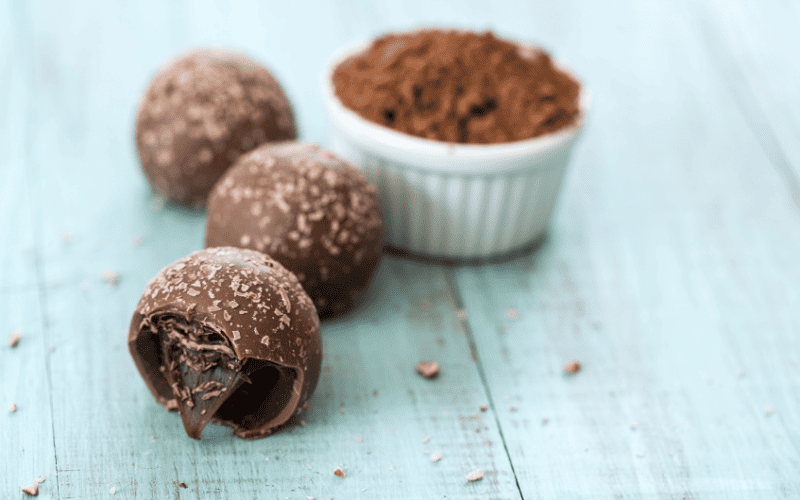 How to Make 15 Paleo Halloween Candy Recipes That Are Scary Good Kelly Bejelly Pecan truffles captured up close, arranged on a textured blue wooden surface.