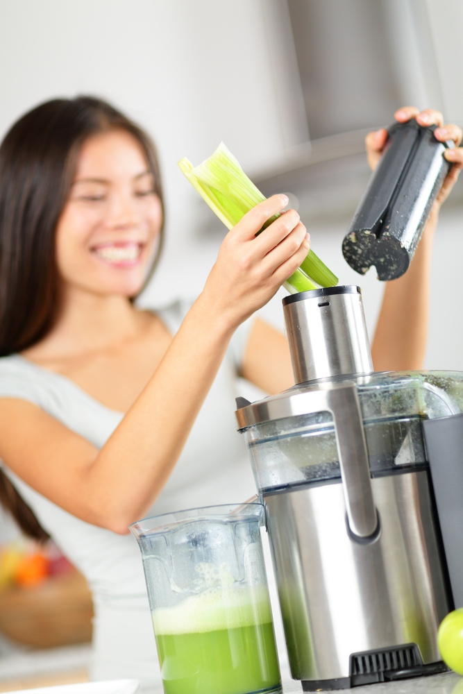 Best Juicer for Celery Kelly Bejelly Woman putting celery into a juicer to make fresh celery juice.