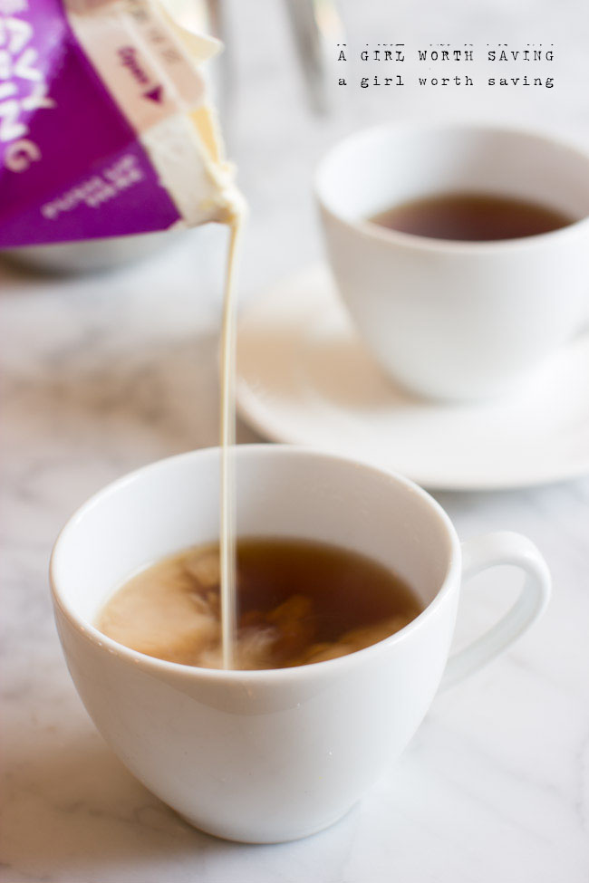 A cup of Dirty Chai Latte with heavy cream being poured into it 