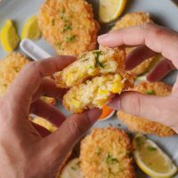 woman holding deep fried corn nuggets in her hand