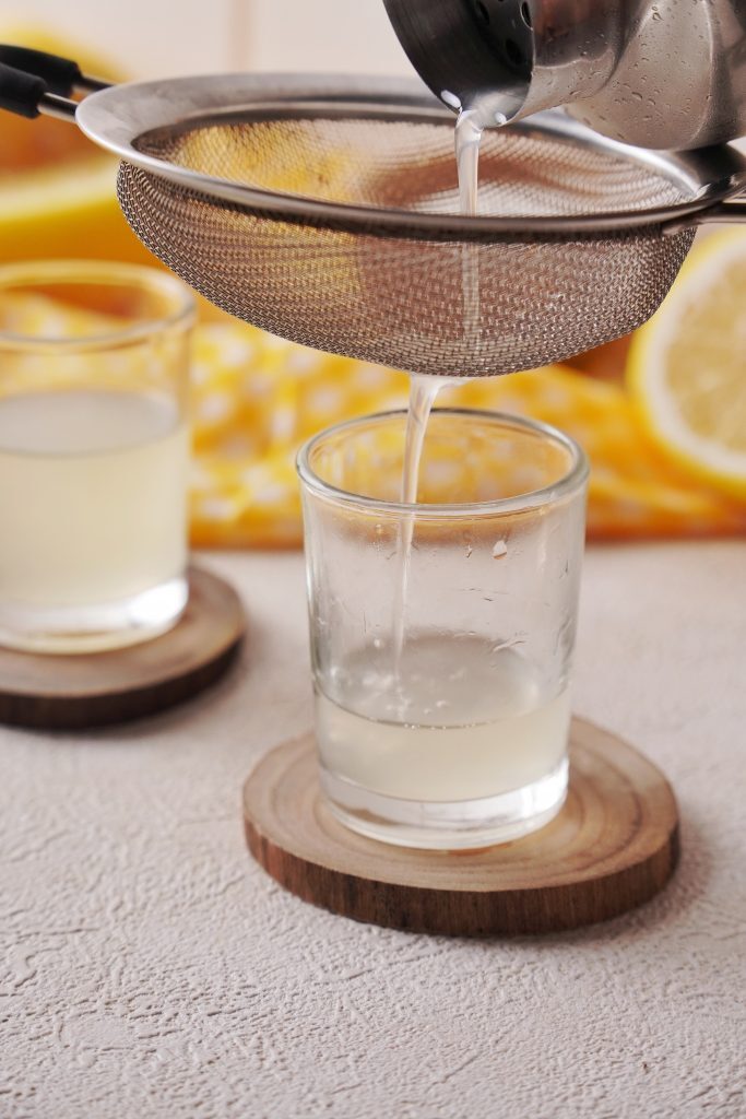 Pouring lemon drop shot into a glass 