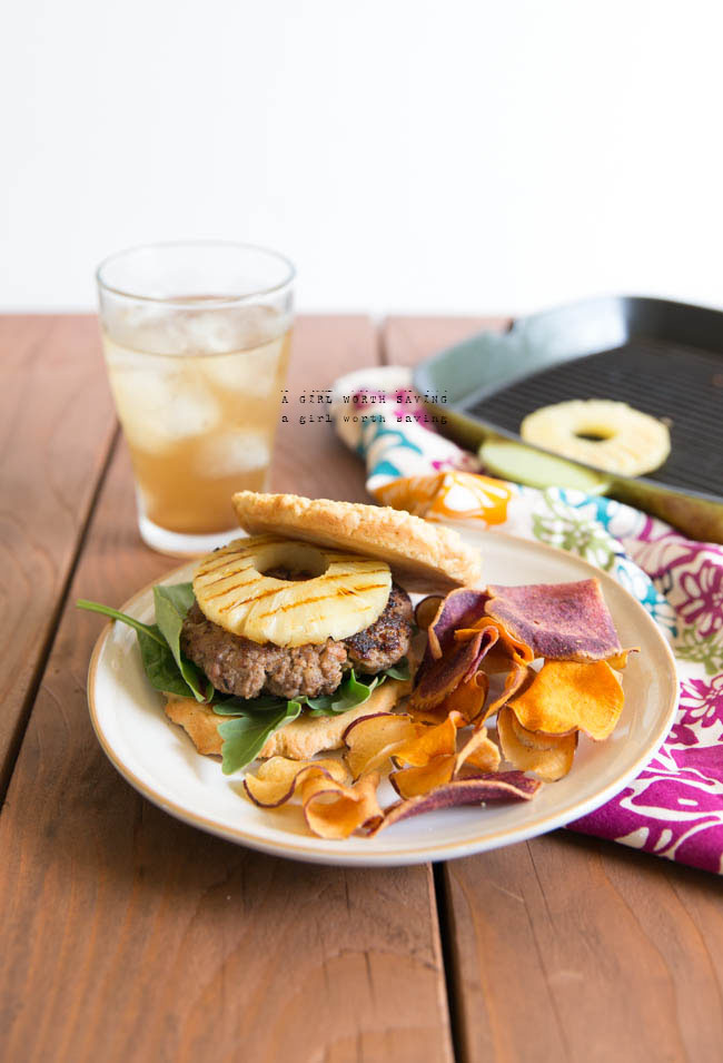 Hawaiian burgers on a plate with grilled pineapple in the background