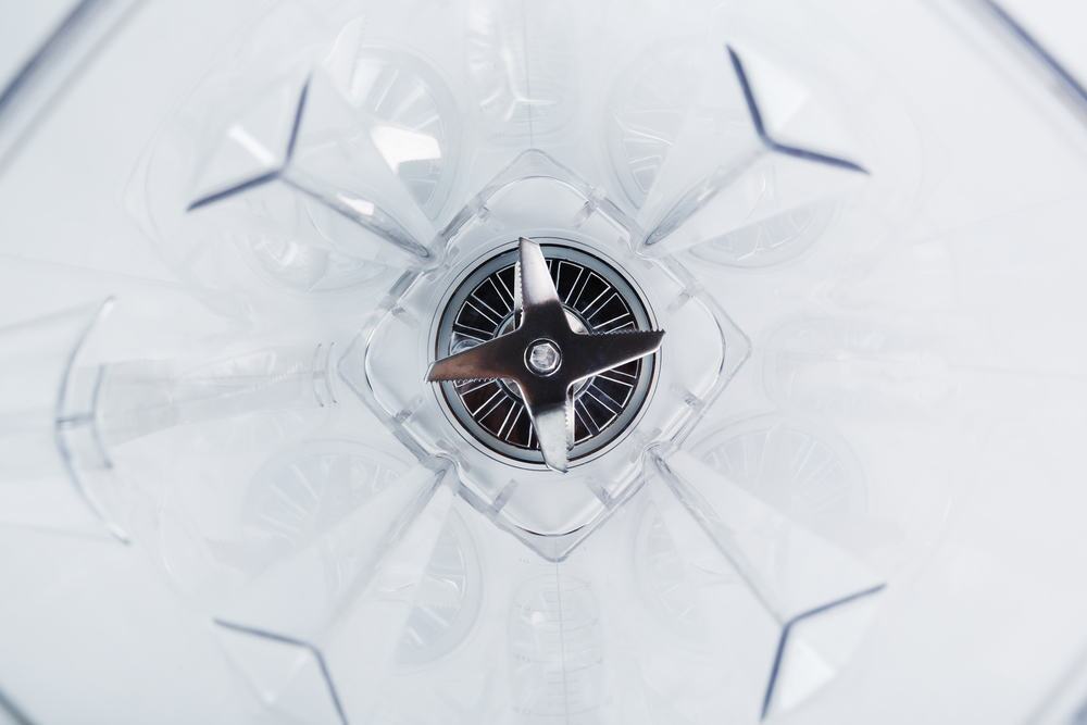 Best Blender Under 100 Kelly Bejelly Close-up of a blender glass shot from the inside with sharp stainless steel blades in the center. Inside view, full screen. Conceptual perspective