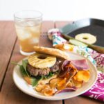 Hawaiian Burgers Kelly Bejelly Hawaiian burgers on a plate with grilled pineapple in the background