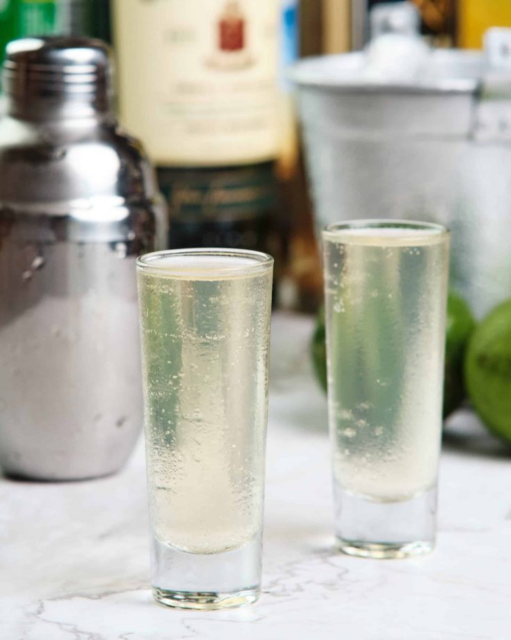 Green Tea Shot Recipe: Refreshing and Bright! Kelly Bejelly close up of green tea shot with limes and ice in the background